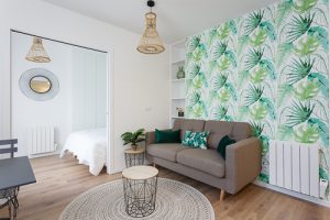 Vue d'un salon avec un papier peint à feuillage tropical
