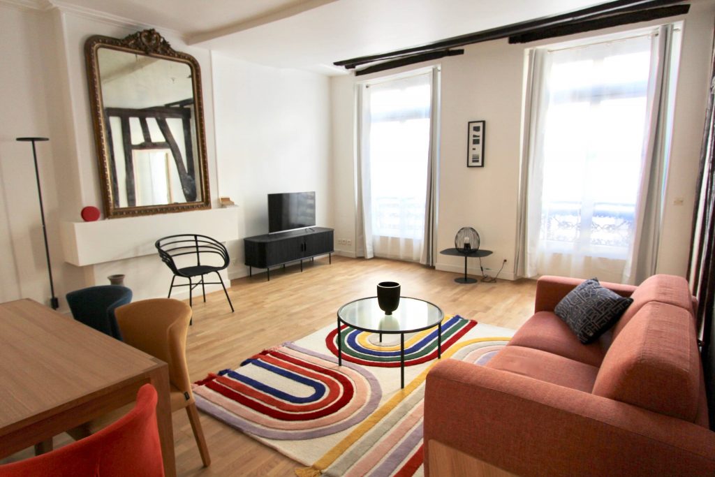 photo d'un salon avec cheminée poutres et mobilier coloré